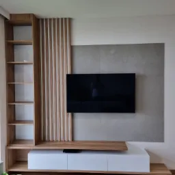 Nowoczesna zabudowa ściany z telewizorem: drewniany regał z półkami, dekoracyjne pionowe lamele, biała szafka RTV z drewnianą półką i szary panel ścienny.