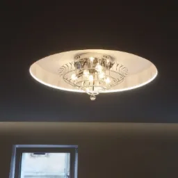 Kryształowy żyrandol z okrągłą obudową zamontowany na ciemnoszarym suficie w pomieszczeniu z dwoma oknami.