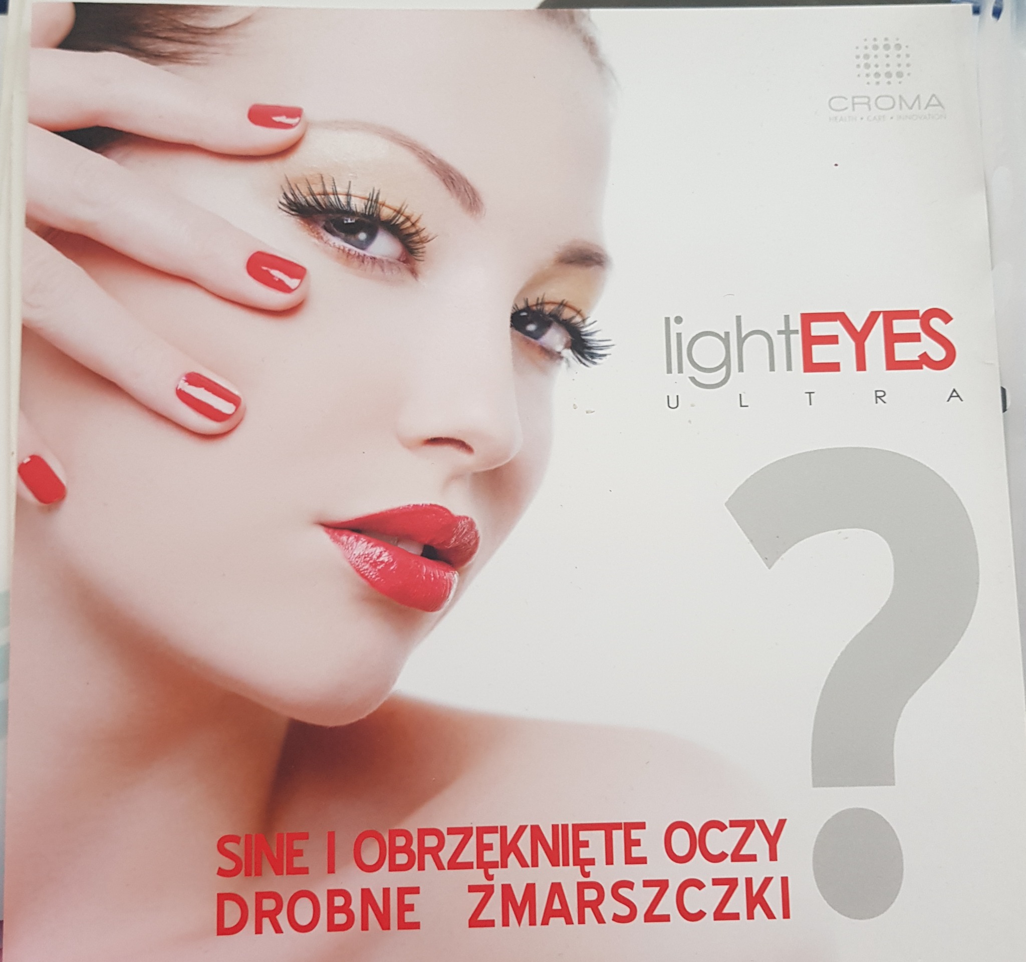 Reklama zabiegu LightEyes Ultra w Raciborzu, przedstawiająca zbliżenie twarzy kobiety z czerwonymi ustami i paznokciami, z tekstem o redukcji cieni i obrzęków pod oczami oraz zmarszczek.