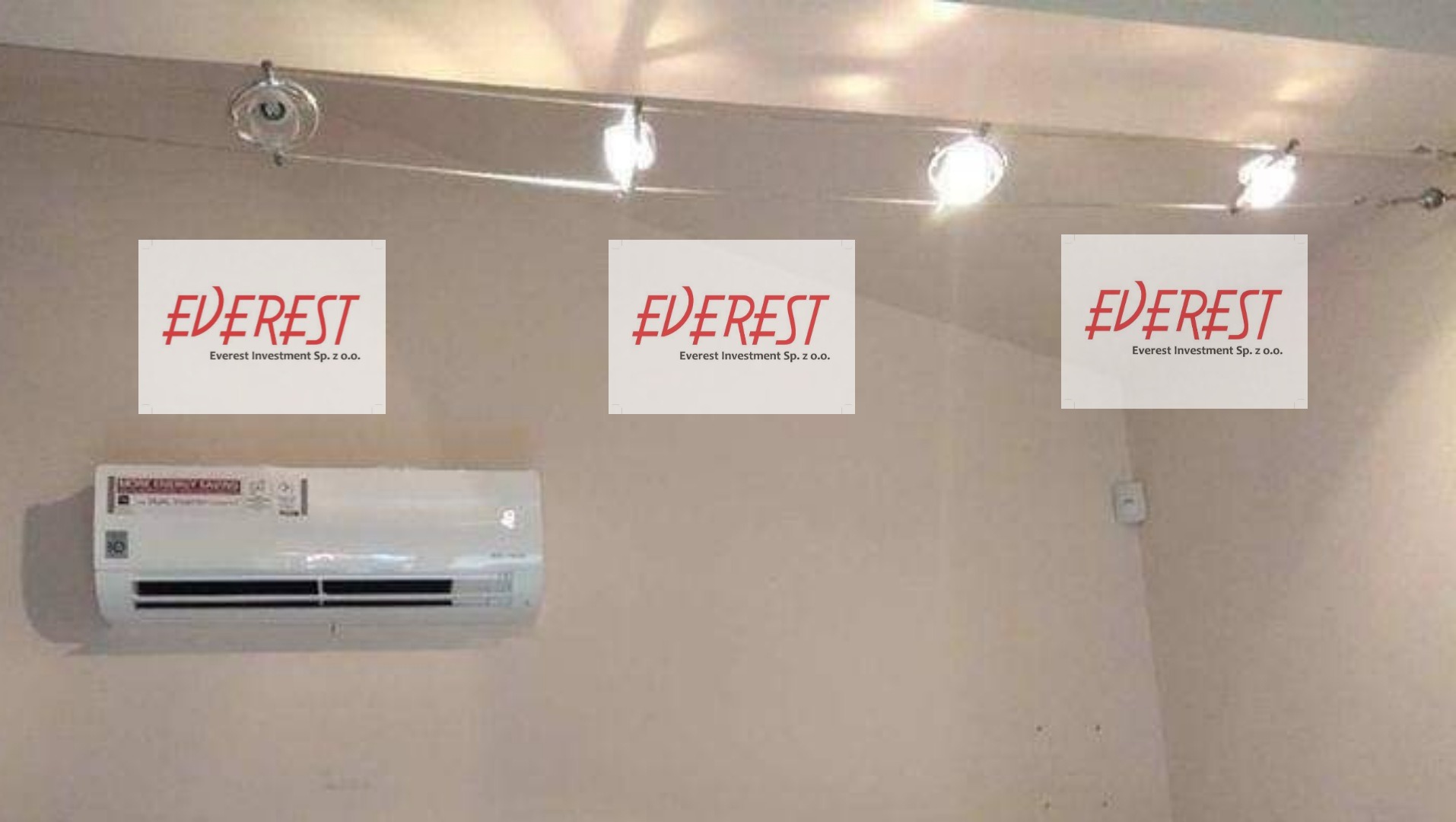 Zamontowana klimatyzacja z naklejonym logo firmy Everest Investment Sp. z o.o., oświetlona punktowymi lampami sufitowymi.