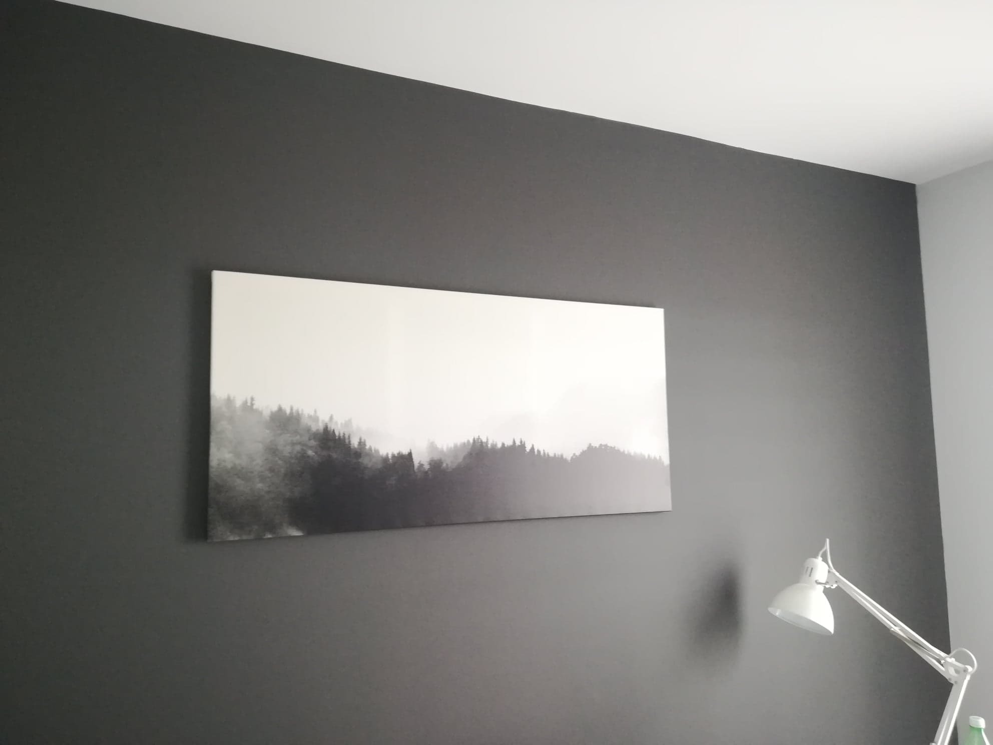 Ściana w odcieniach szarości z obrazem przedstawiającym mglisty las i lampką biurkową.