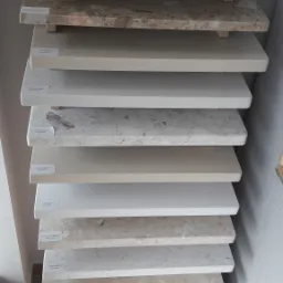 Ekspozycja próbek blatów z różnych materiałów i wariantów kolorystycznych, ułożonych jeden na drugim, z widocznymi etykietami z nazwami.