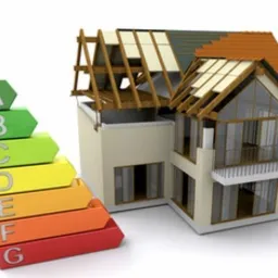 Wizualizacja domu w trakcie budowy z nałożoną grafiką przedstawiającą klasę energetyczną budynku od A do G, prezentowaną za pomocą kolorowych strzałek.