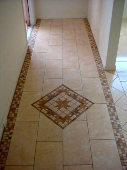 Beżowa podłoga z płytek ceramicznych w Krakowie z dekoracyjnym, mozaikowym obramowaniem i centralnym wzorem w kształcie rombu z motywem kwiatowym.