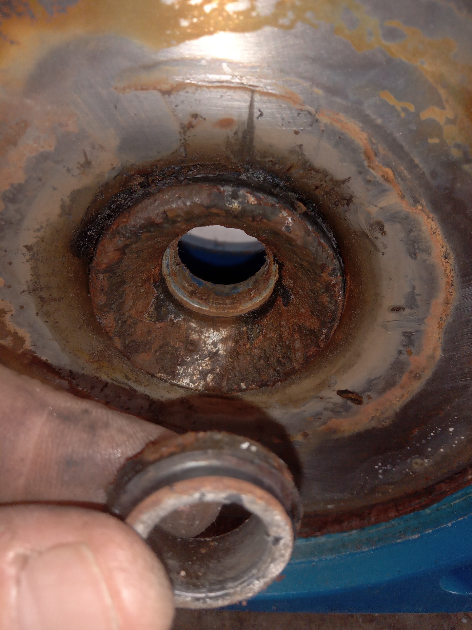 Zardzewiałe gniazdo rury, widoczne ślady korozji i osadów, element instalacji wodnej w trakcie demontażu.