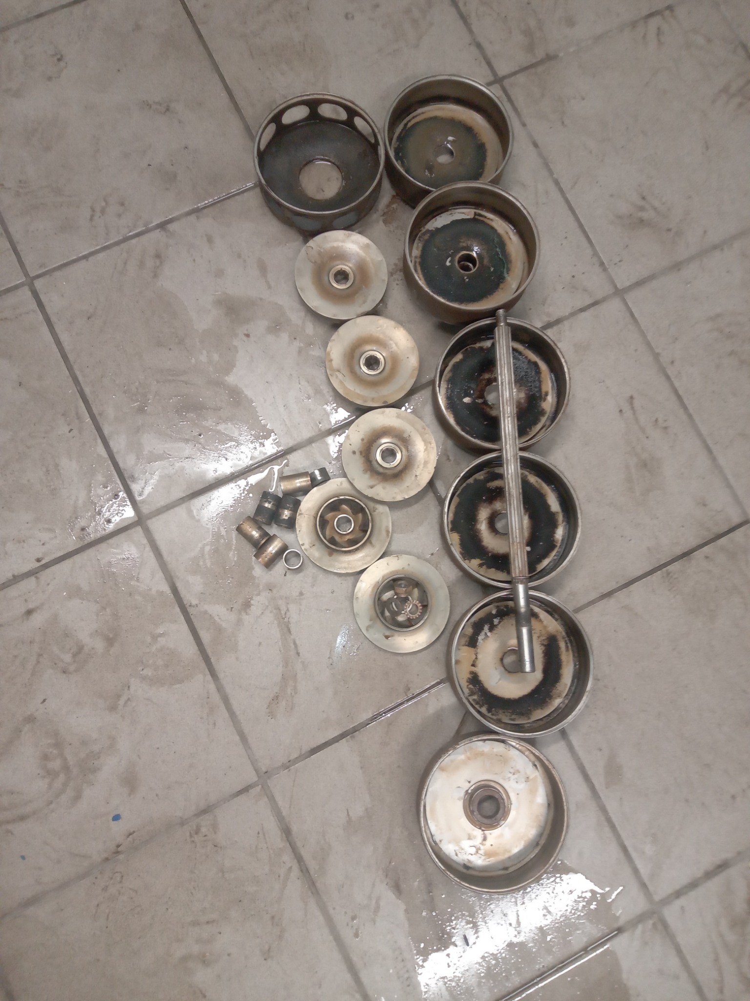 Rozłożone na podłodze, metalowe elementy pieca centralnego ogrzewania, widoczne ślady użytkowania i nagaru, przygotowane do czyszczenia lub wymiany.