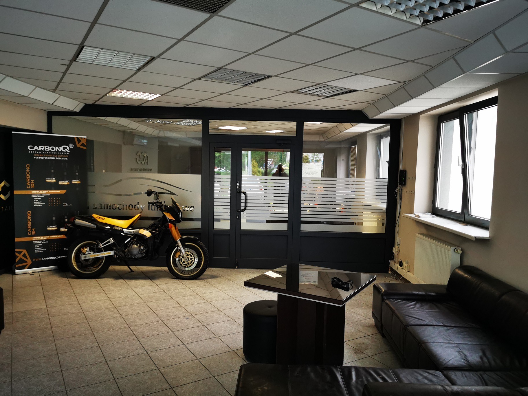 Motocykl Yamaha w poczekalni z logo CarbonQ na banerze, sugerujący detailing ceramiczny.