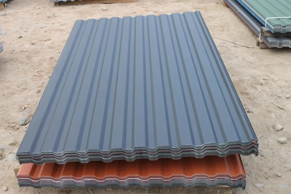 Stos arkuszy blachy trapezowej w kolorze grafitowym i ceglastym, ułożonych na ziemi.