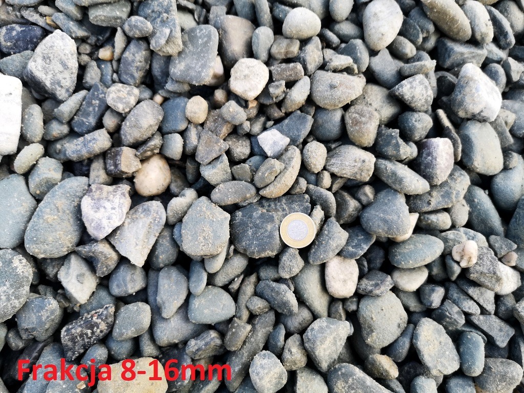 Żwir frakcji 8-16mm z monetą jednozłotową dla porównania wielkości, oświetlony naturalnym światłem.