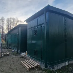 Dwa zielone, stalowe kontenery w Rybniku, ustawione obok siebie na ziemi, z widocznymi paletami drewnianymi z przodu. Kontenery posiadają drzwi i kratki wentylacyjne.