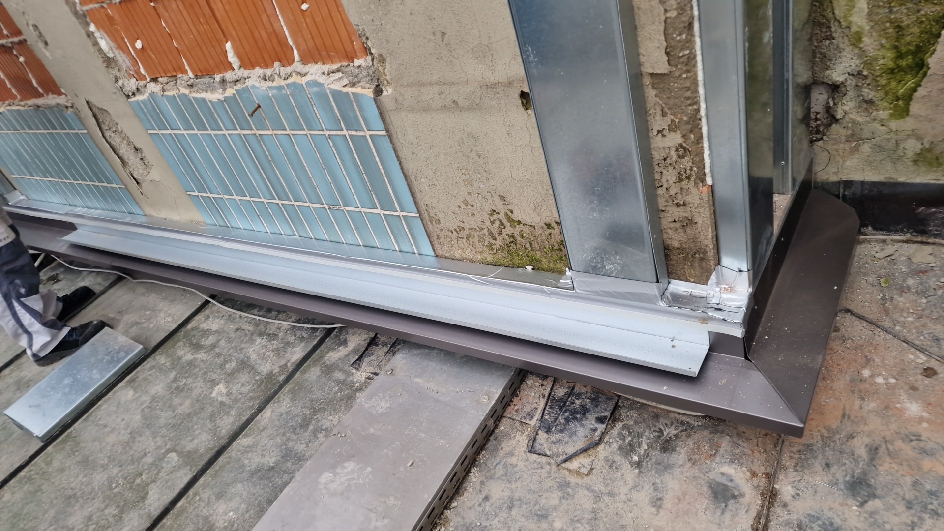 Fragment montażu konstrukcji z profili stalowych przy ścianie z widoczną izolacją i fragmentami muru