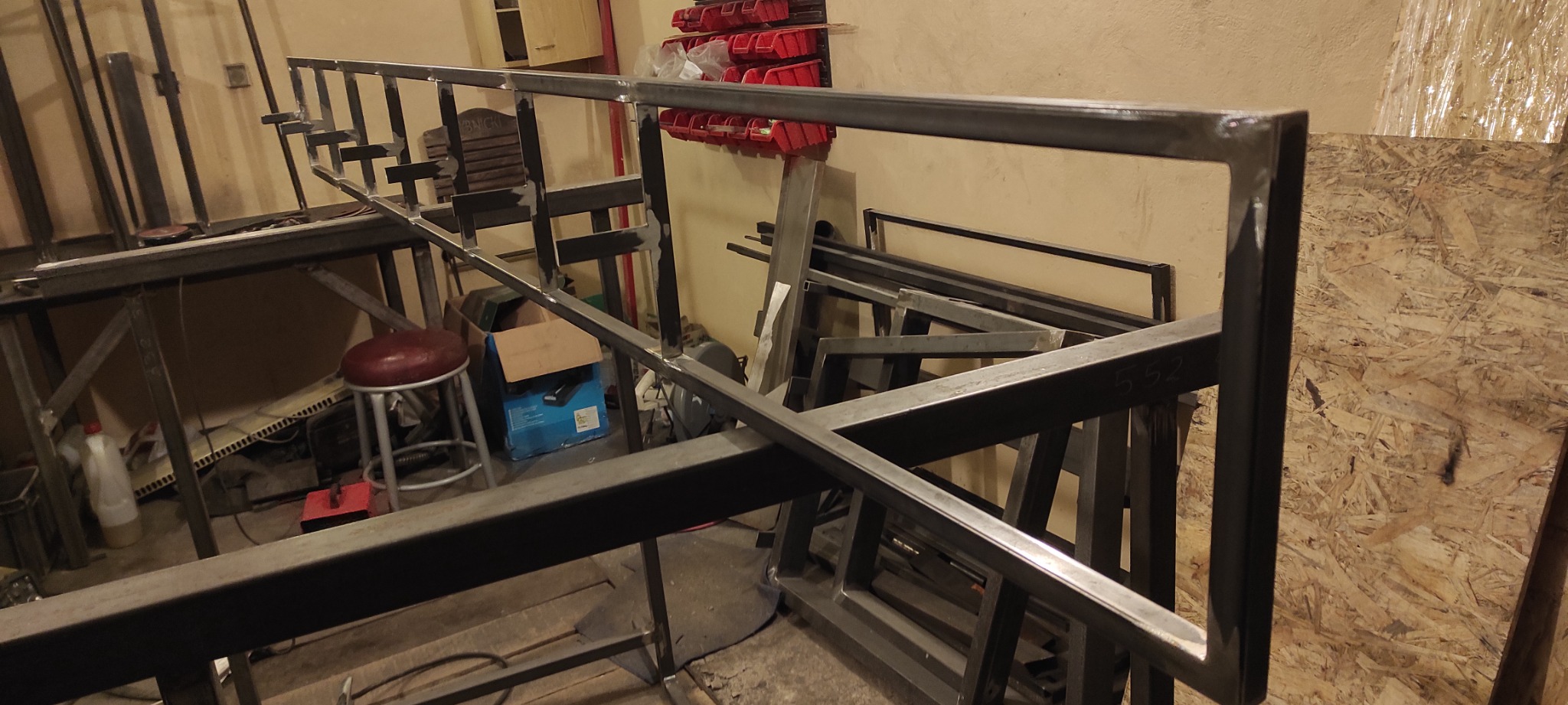 Konstrukcja schodów z metalu w trakcie spawania, widoczne spawy i elementy mocujące w surowym warsztacie.