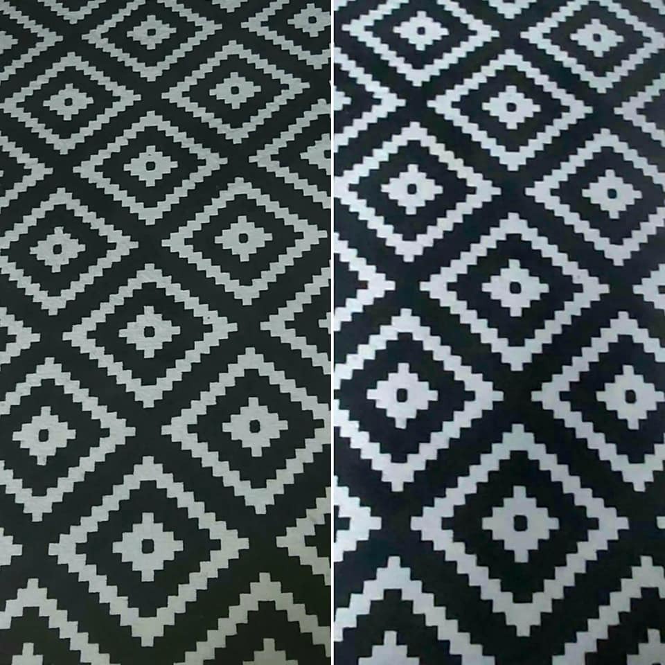 Fragment czarno-białego dywanu z geometrycznym wzorem rombów i kwadratów, widoczne delikatne różnice w odcieniach czerni po lewej i prawej stronie.