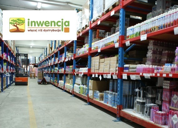 Magazyn z regałami pełnymi różnorodnych produktów, w tle wózek widłowy, w lewym górnym rogu logo firmy 'Inwencja'.