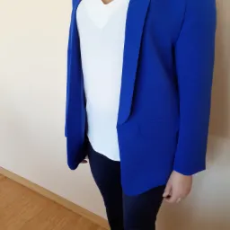 Kobieta prezentuje kobaltowy żakiet z jedną kieszenią, założony na białą bluzkę z dekoltem w serek i czarne spodnie.