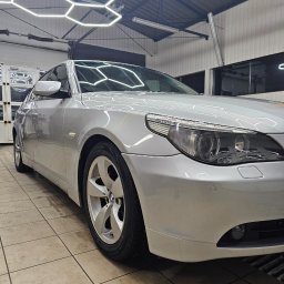 Nice Cars Studio Sp. z o.o. - Błyszczący, srebrny samochód BMW po umyciu w myjni, widoczny z niskiej perspektywy, z heksagonalnymi lampami LED na suficie. Czyste felgi i karoseria.