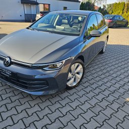 Nice Cars Studio Sp. z o.o. - Szary Volkswagen Golf po detailingu, z widocznym logo Nice Cars Studio na tablicy rejestracyjnej, zaparkowany na kostce brukowej przed budynkiem.