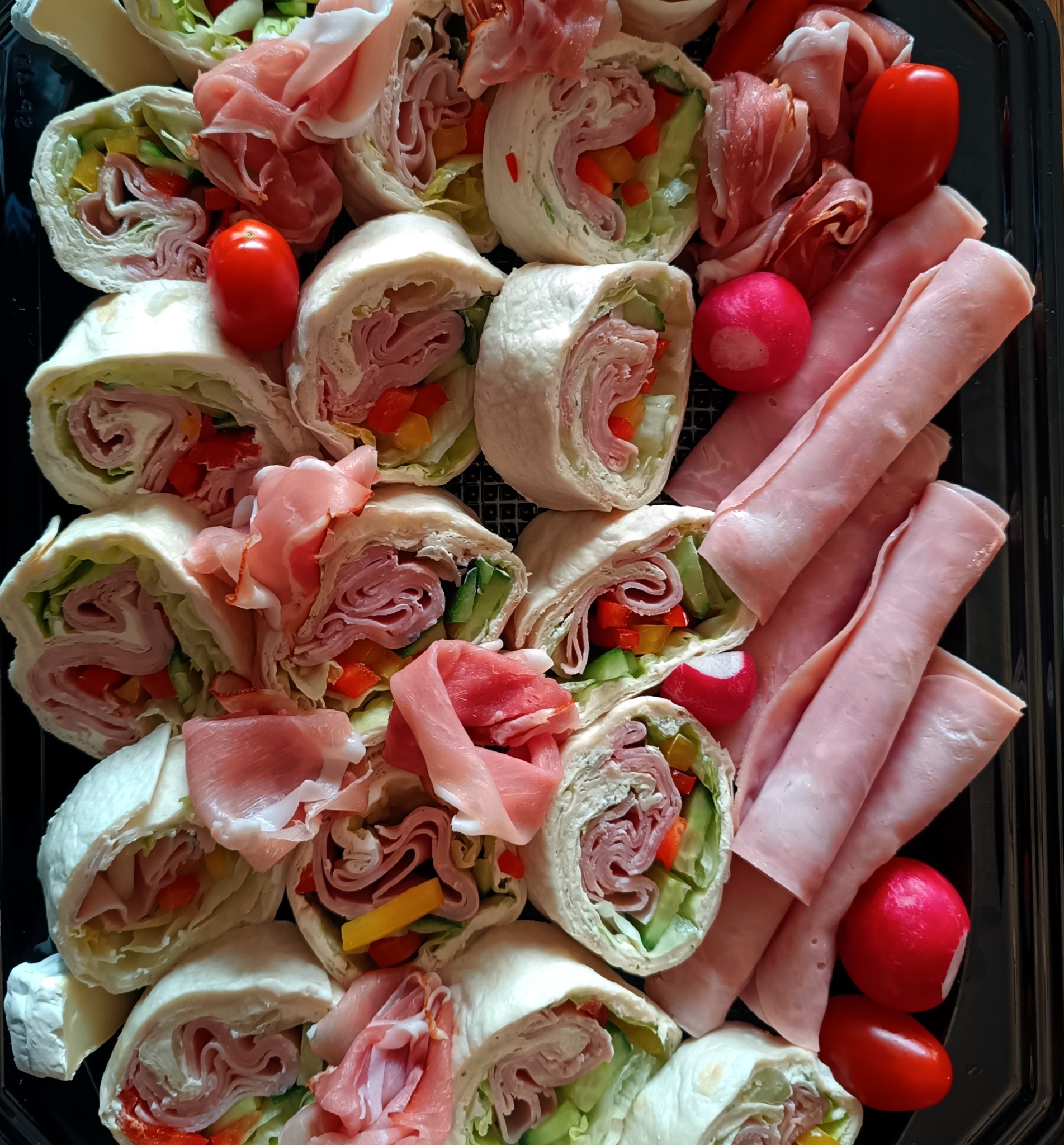 Elegancka taca z roladkami z tortilli, szynką parmeńską, wędliną, rzodkiewkami i pomidorkami koktajlowymi, idealna na catering firmowy lub świąteczny.
