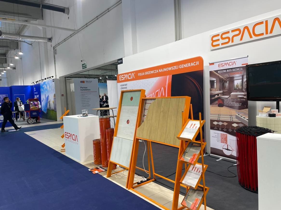 Ekspozycja stoiska firmy Espacia prezentująca folię grzewczą najnowszej generacji oraz węglową matę grzewczą Nanoheat na targach. Widoczne próbki materiałów, roll-up reklamowy i ulotki informacyjne.