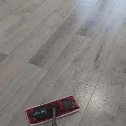 Jasne panele podłogowe imitujące drewno, świeżo umyte mopem Vileda, w rogu widoczny fragment białej ściany i okno.