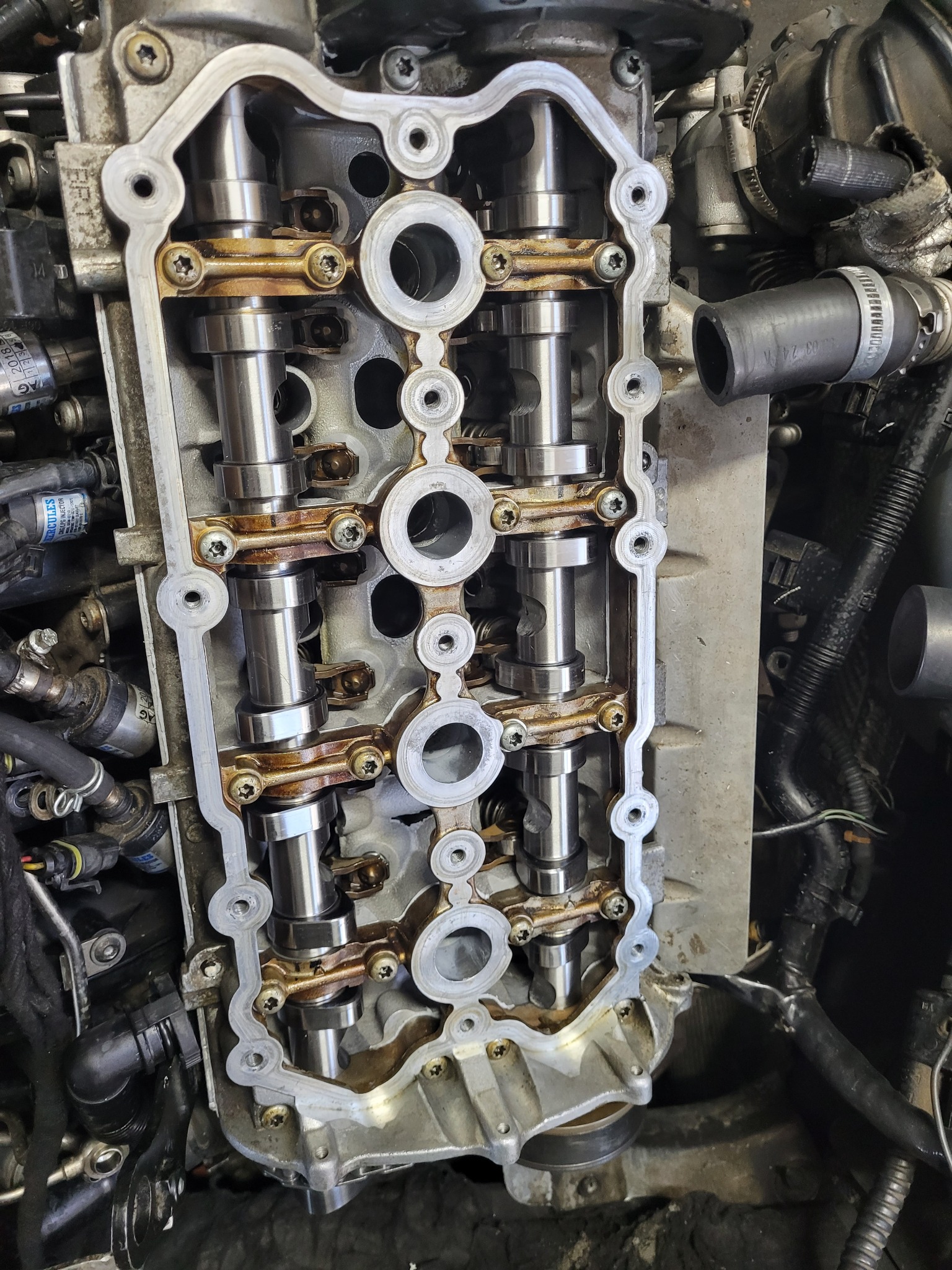 Zdjęcie silnika samochodowego z widocznymi wałkami rozrządu i elementami układu rozrządu, po zdjęciu pokrywy zaworów, ukazujące stan wnętrza silnika podczas naprawy lub diagnostyki.