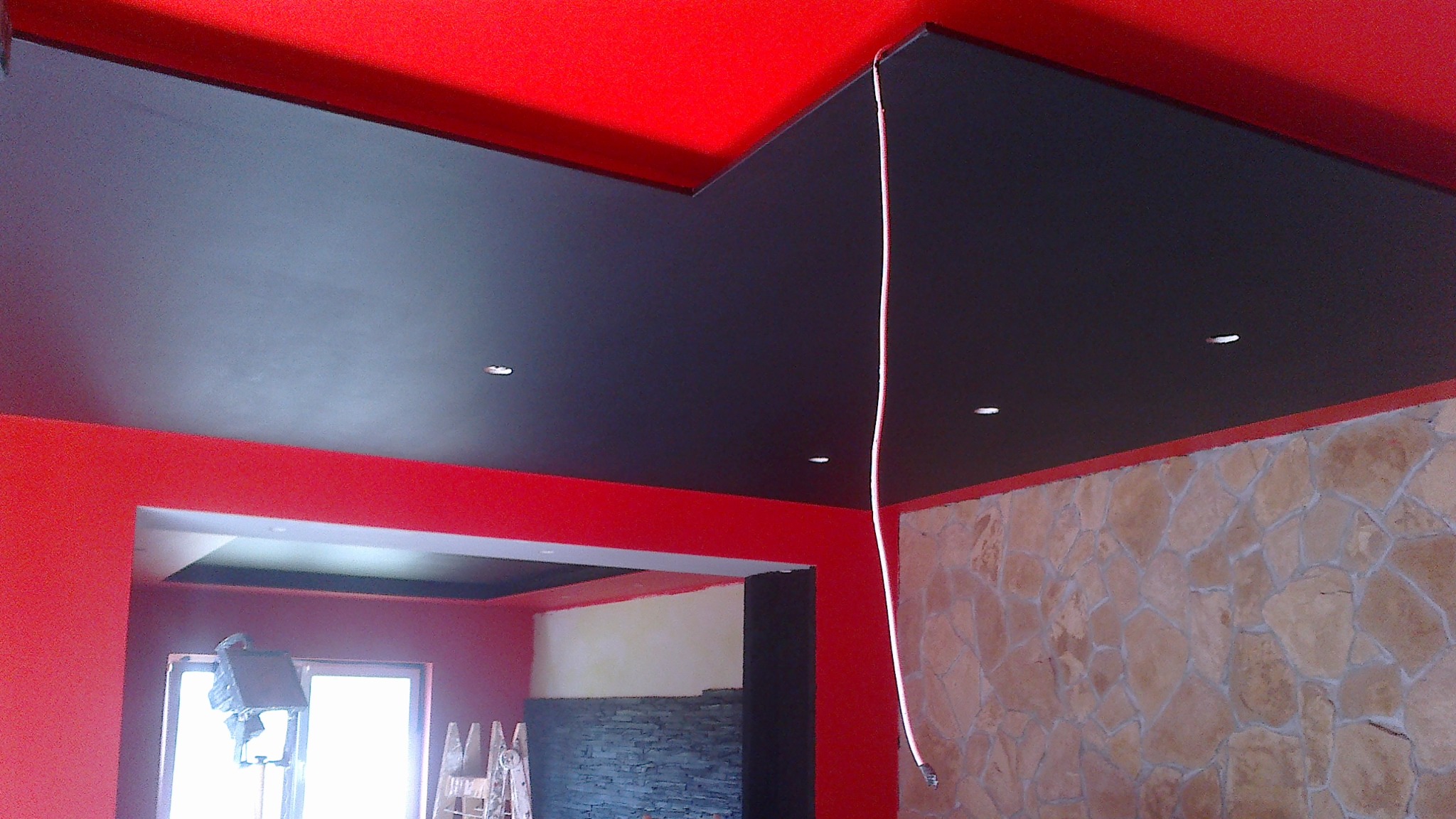 Czerwono-czarne malowanie sufitu i ścian w Skarżysko-Kamiennej, z widocznym oświetleniem punktowym i fragmentem ściany z kamienia dekoracyjnego.