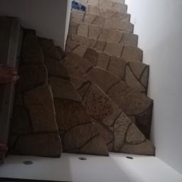 Mirella Mandla Górzyńska - Schody wewnętrzne wykończone panelami imitującymi kamień, widok z dołu, z fragmentem stopy w lewym górnym rogu.