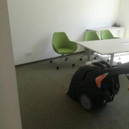 BlueService Sp. z o.o. - Profesjonalny odkurzacz piorący Procarpet 50 podczas czyszczenia wykładziny dywanowej w biurze. Widoczne zielone krzesła biurowe na kółkach i biały stół konferencyjny.