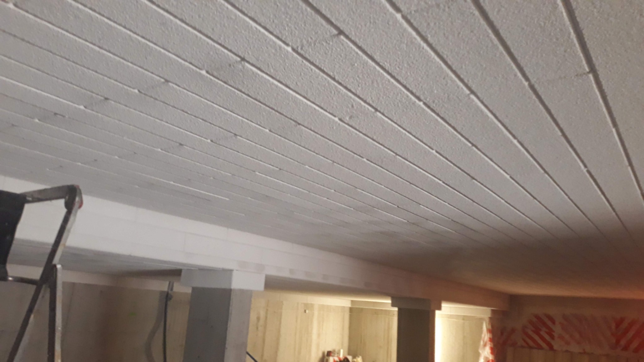 Poddasze z ociepleniem natryskowym, widoczna drabina i elementy konstrukcyjne budynku