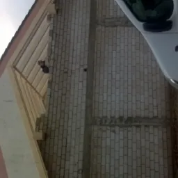 Budowa domu w trakcie: widoczny fragment ściany z białego bloczka oraz drewniana konstrukcja dachu, pracownik widoczny wewnątrz konstrukcji, obok zaparkowany biały samochód dostawczy.