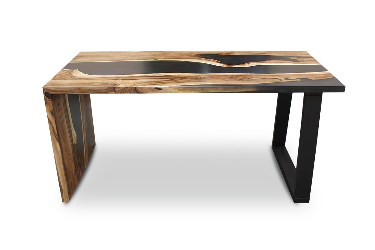 Stół z blatem z litego drewna z żywicą epoksydową w kolorze czarnym, osadzony na asymetrycznych nogach: jednej drewnianej i jednej metalowej w kształcie trapezu.