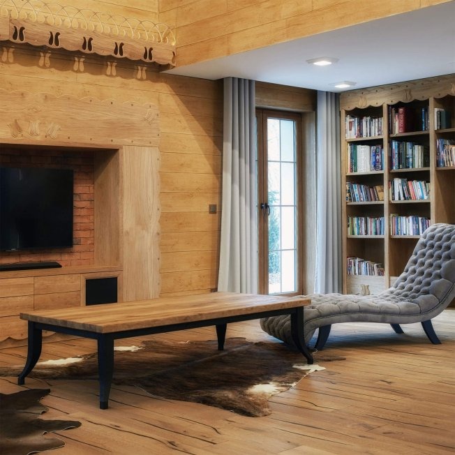 Drewniane wnętrze w stylu rustykalnym w Czarnej Sędziszowskiej: boazeria, regał na książki, stolik kawowy z ciemnymi nogami i skórzany dywan na podłodze.