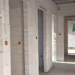 Tynki Maszynowe - Wnętrze w stanie surowym: ściany z białego betonu komórkowego, widoczne otwory drzwiowe, instalacja elektryczna w peszlach, sufit betonowy z widocznymi elementami drewnianymi.