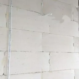 Instalacja elektryczna w korytkach na ścianie z betonu komórkowego, widoczne puszki instalacyjne i przewody.