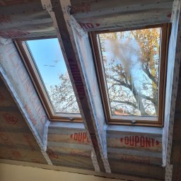 Perfekt Mal Adrian Szpora - Dwa okna dachowe w trakcie montażu, zabezpieczone folią i taśmą Tyvek, widok od wewnątrz na niebo i drzewa. Etap prac wykończeniowych, izolacja poddasza.