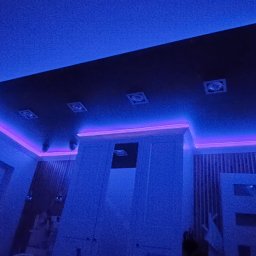 FachGro usługi remontowe - Podwieszany sufit z oświetleniem LED w kolorze fioletowym i niebieskim. Cztery kwadratowe lampy w suficie. Widok z dołu, wnętrze w chłodnej tonacji.