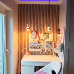 FachGro usługi remontowe - Pokój młodzieżowy z biurkiem, drewnianą ścianą z lamelami i podwieszanym sufitem z niebieskim oświetleniem LED. Na biurku tablica z akcesoriami.