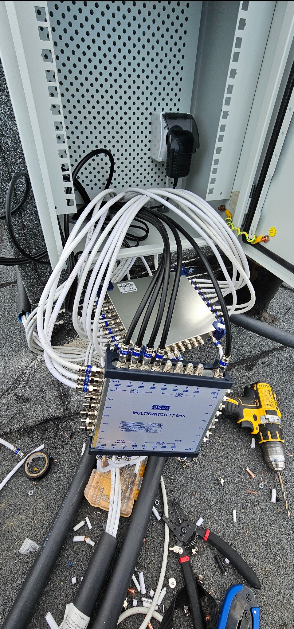 Instalacja multiswitcha Telmor TT 9/16 z podłączonymi kablami koncentrycznymi i narzędziami na dachu. Widoczna skrzynka instalacyjna i przewody uziemiające.