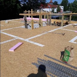 Permian Sp. z o.o. - Wznoszenie konstrukcji domu murowanego: widok z góry na fundamenty, bloczki, drewniane podpory, izolację styropianową i materiały budowlane na placu budowy w słoneczny dzień.