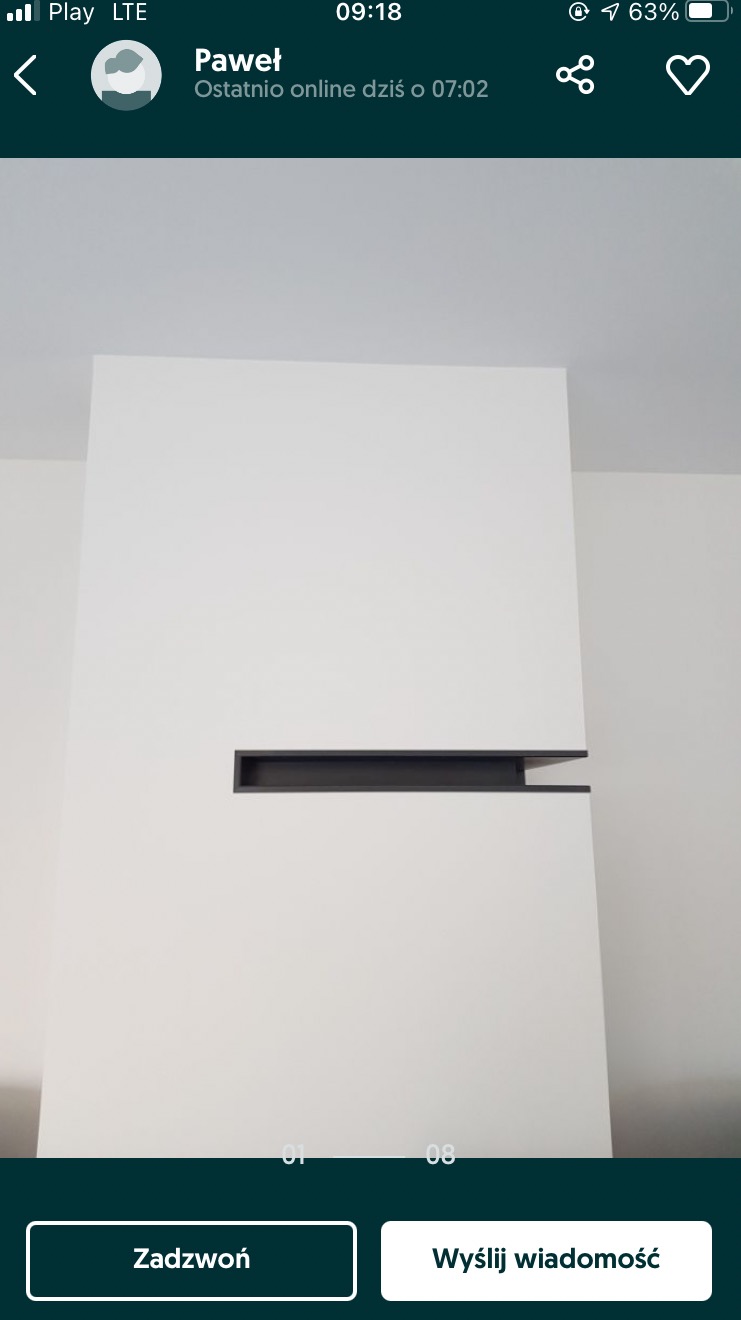 Minimalistyczna ściana z białymi panelami i poziomym, ciemnym wnęką oświetleniową, widoczne fragmenty sufitu i sąsiedniej ściany.