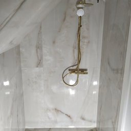 Łazienka bryła płytki imitacja marmuru 120x60  z odpływem liniowym i aramaturą w kolorze złotym. 