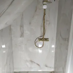 Łazienka bryła płytki imitacja marmuru 120x60 z odpływem liniowym i aramaturą w kolorze złotym.