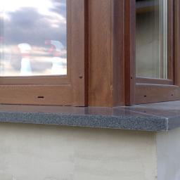 Przedsiębiorstwo Remontowo -Budowlane Emirem Maciej Cieślak - Zamontowany, ciemnoszary parapet z granitu pod brązowym oknem PCV, widoczny fragment surowej elewacji budynku.