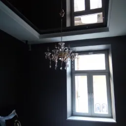 Eleganckie wnętrze sypialni z ciemnymi ścianami, kryształowym żyrandolem, oknem z białymi ramami i łóżkiem z wzorzystą pościelą, widok na sufit z lustrzanym panelem.