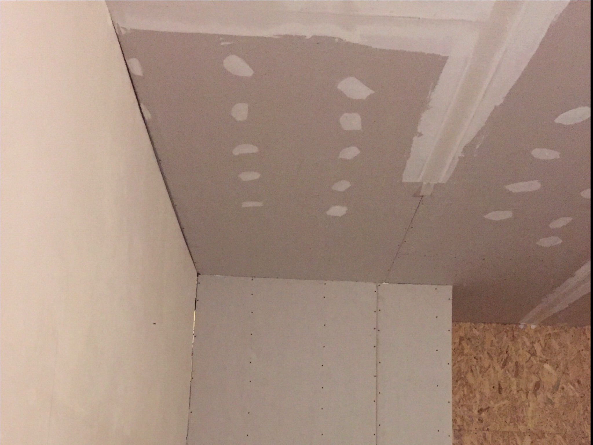 Wnętrze w trakcie wykańczania: ściany i sufit pokryte płytami gipsowo-kartonowymi, widoczne szpachlowane łączenia i miejsca po wkrętach.