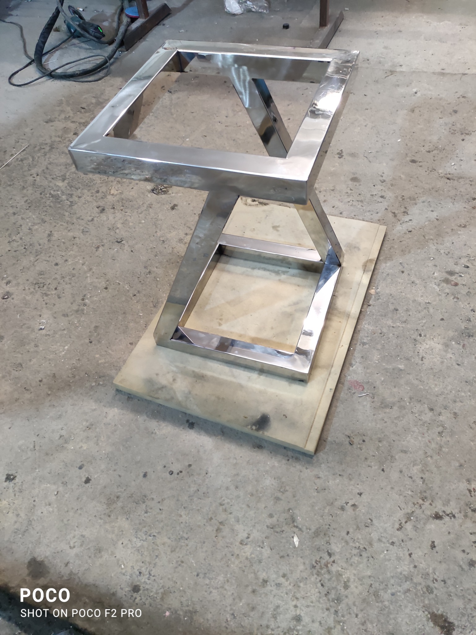 Stalowa podstawa stołu z profili zamkniętych, spawana, polerowana na wysoki połysk, leżąca na płycie z tworzywa w warsztacie.