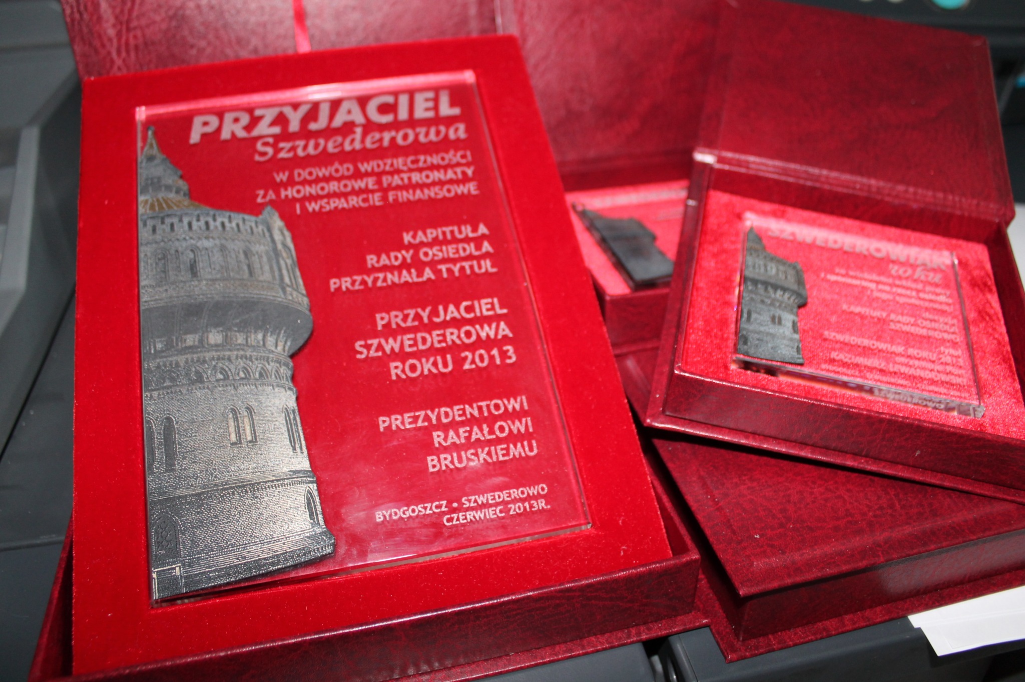 Pamiątkowe statuetki w czerwonych pudełkach z metalową miniaturą wieży ciśnień, upamiętniające tytuł Przyjaciela Szwederowa Roku 2013, wręczone Prezydentowi Rafałowi Bruskiemu.