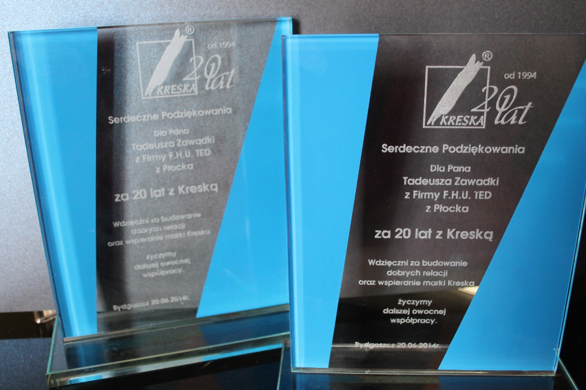 Dwa szklane trofea z niebieskimi akcentami, wygrawerowane z podziękowaniami dla Tadeusza Zawadzkiego z firmy F.H.U. TED z Płocka za 20 lat współpracy z Kreską, z datą Bydgoszcz 20.06.2014.