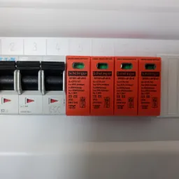 Rozdzielnica elektryczna z czterema ogranicznikami przepięć Schelinger SPD01-4P-B+C, widoczne wyłączniki Eaton IS-63/3 i oznaczenia numerów obwodów.