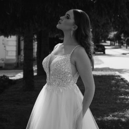 Karol Pałys - Czarno-białe zdjęcie panny młodej w bogato zdobionej sukni, spoglądającej w górę podczas sesji w Jarosławiu, z widocznym fragmentem drzewa i zabudowań w tle.